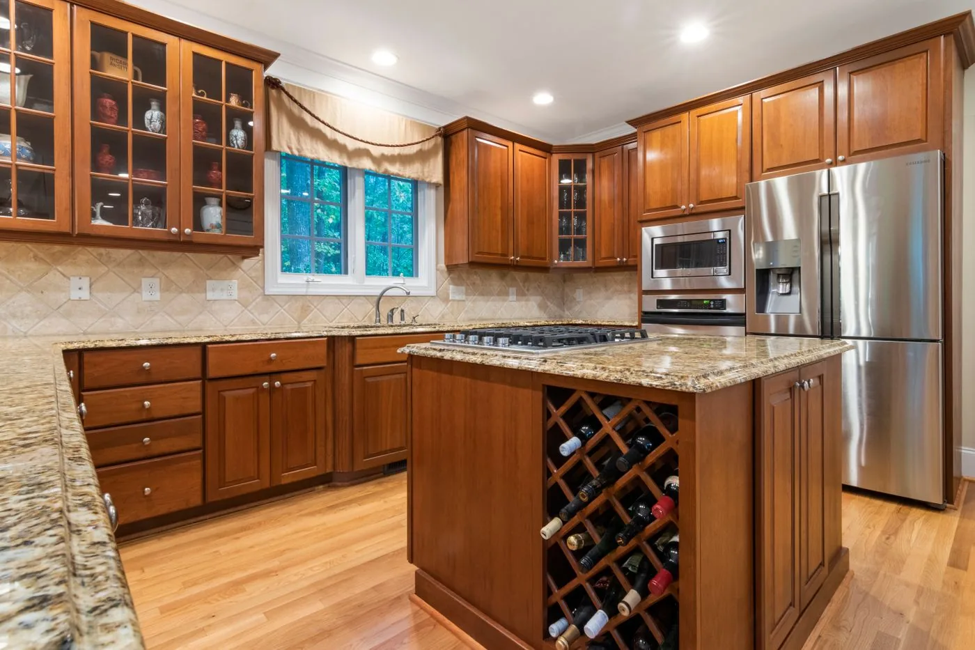 A kitchen with wood cabinet doors and a newer stone countertop