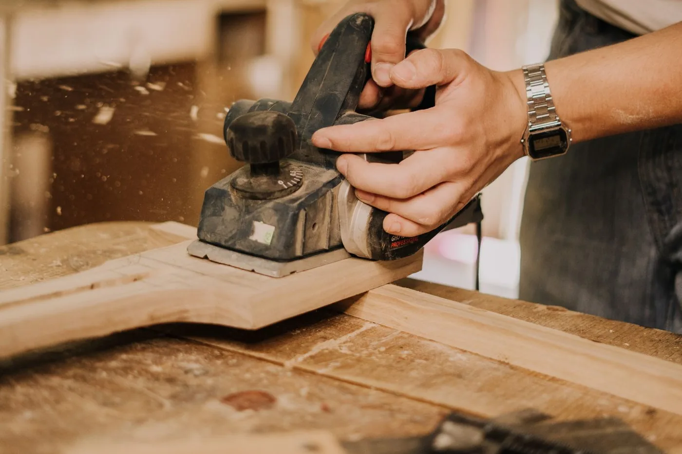 A carpenter smoothing a wooden surface with an electric sander