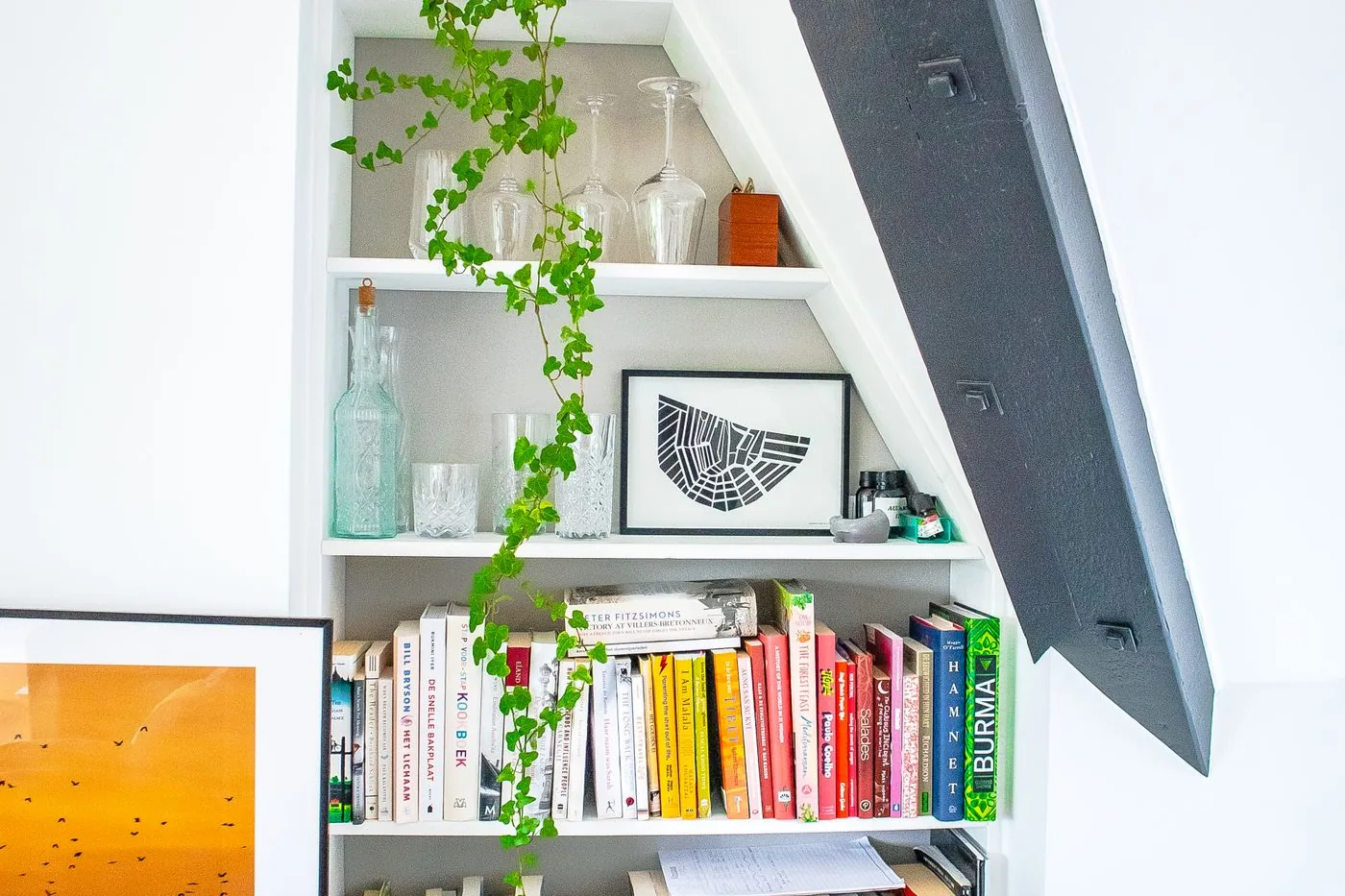 A fitted bookshelf built into the wall of a room under a staircase