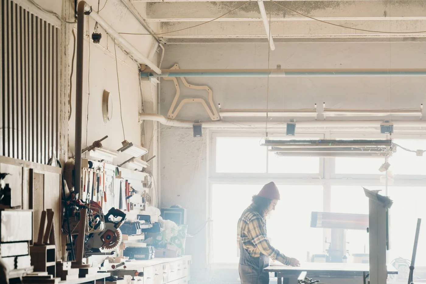 A carpenter at work in a well-lit workshop full of tools