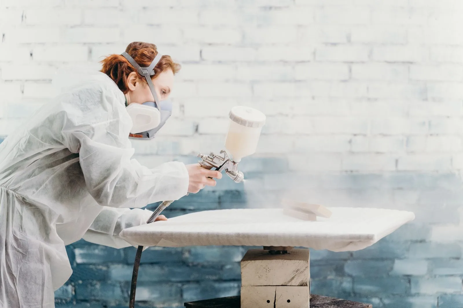 A finisher in protective gear spraying a door front — cabinet painting in Murfreesboro, TN