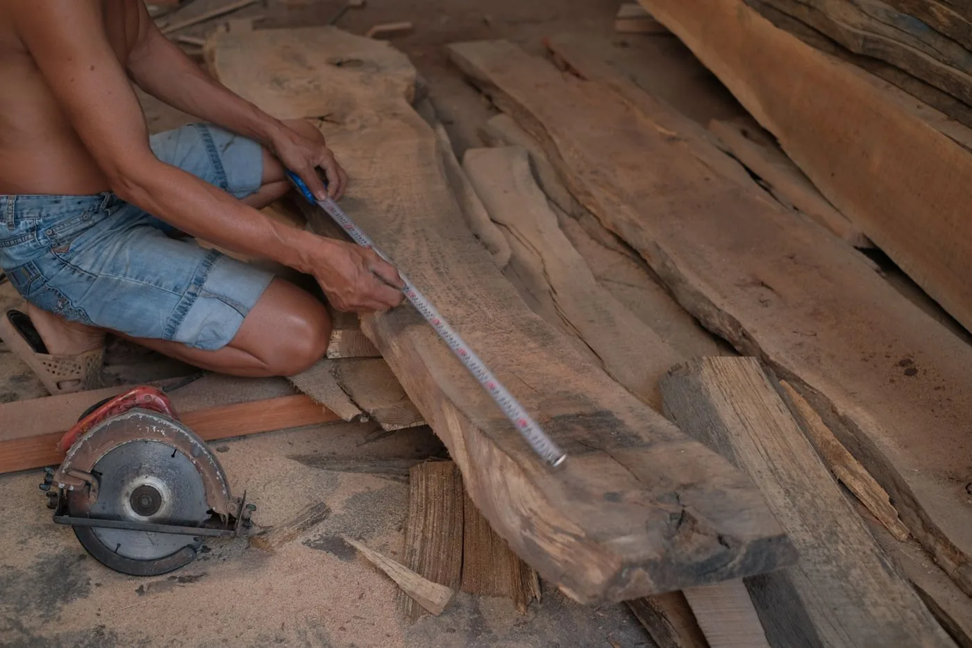 A carpenter measuring a wooden plank at the bench