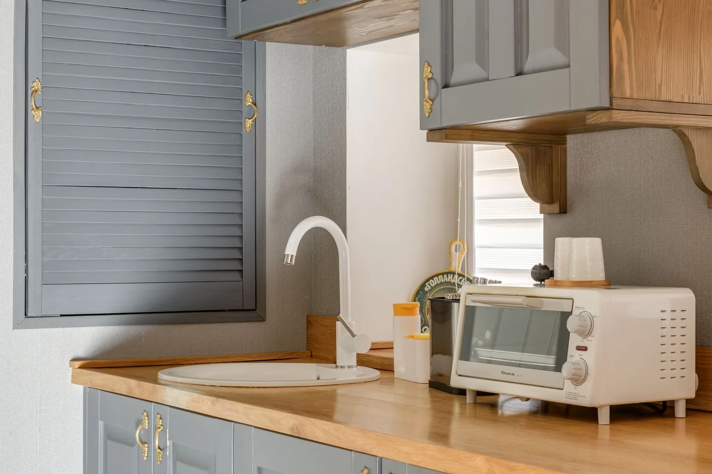 A kitchen of grey cabinet doors and drawer fronts under wooden countertops
