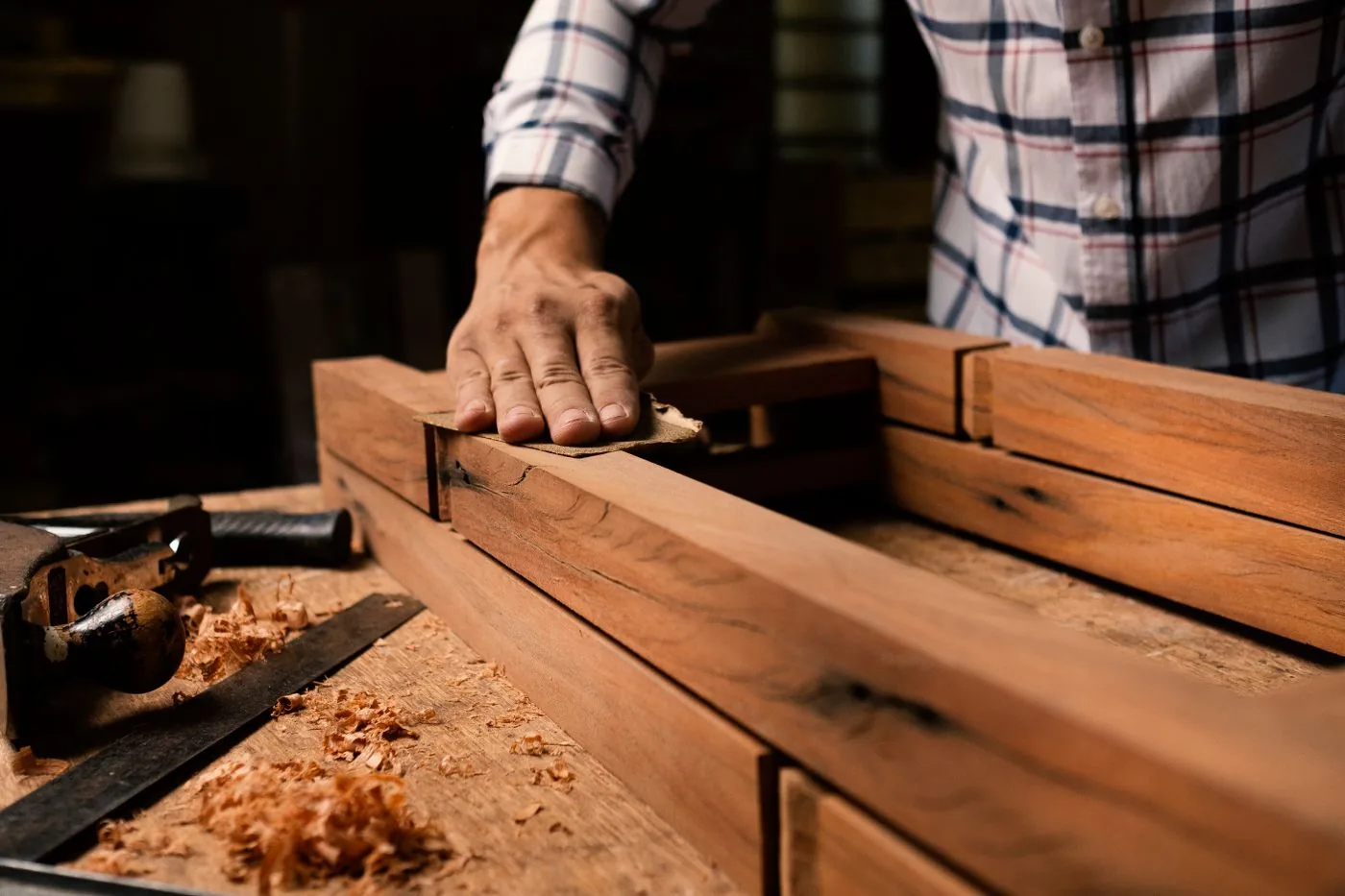 A woodworker smoothing a wooden frame by hand in a workshop