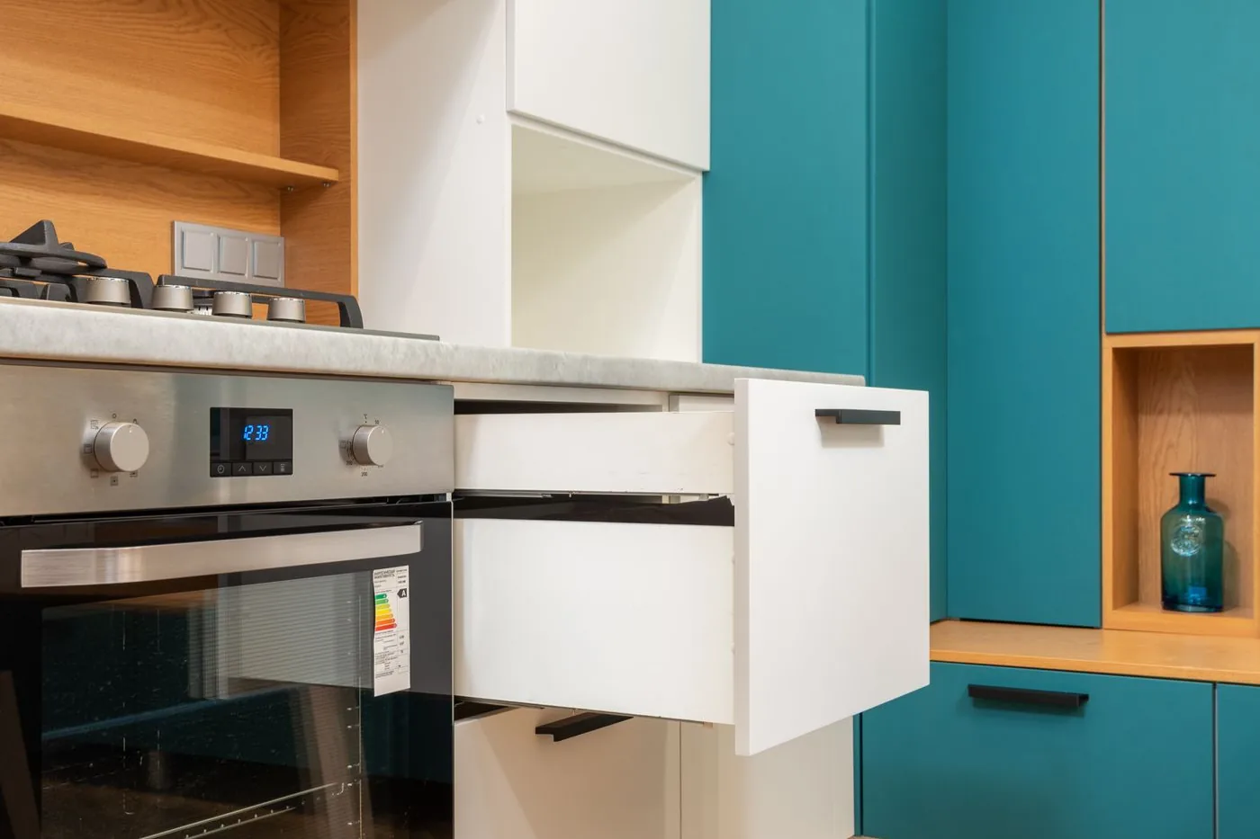 An open cabinet drawer beside the oven in a modern kitchen